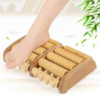 Wooden foot massager with a foot on it, surrounded by green leaves.